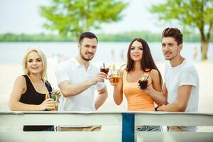 Friends having fun at the bar outdoors, drinking cocktails. photo