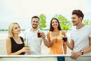 amigos teniendo divertido a el bar al aire libre, Bebiendo cocteles foto