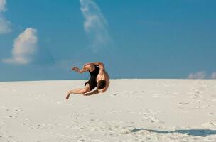 Portrait of young parkour man doing flip or somersault on the sand. photo