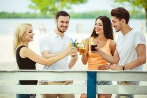 Friends having fun at the bar outdoors, drinking cocktails. photo