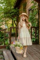 Carefree tween girl with basket of wildflowers standing on doorstep of country house photo