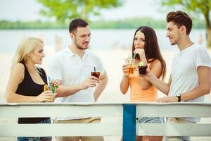 Friends having fun at the bar outdoors, drinking cocktails. photo