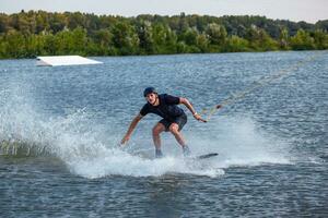 hombre equilibrio en wakeboard remolcado en cable molesto a hacer agarrar de tablero foto