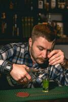 Bartender pouring tequila down spiral stem of bar spoon into shot glass with banana liqueur photo