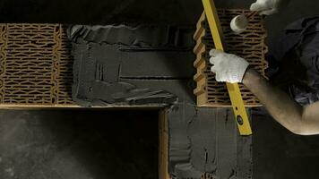 Top view of an industrial worker levelling ceramic brick wall with a wooden hammer. Stock footage. Building new wall of ceramic blocks. photo