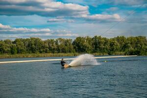 Experienced wakeboarder glides on water with board edge, creating splashes photo