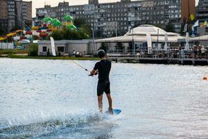 Man in wet suit and protective helmet holding tow rope and balancing on wakeboard photo