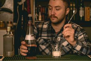 Focused bartender preparing alcoholic cocktail White Russian behind bar counter photo