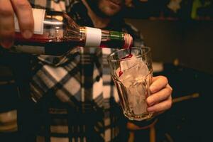 barman preparando refrescante cóctel, torrencial baya jarabe dentro vaso con hielo foto