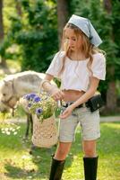 Teen girl plucking flowers on sunny glade on background of grazing horse photo