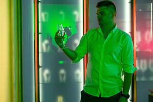 Young man with glass of champagne standing in subdued colorful lighting at nightclub photo