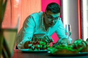 Interested man preparing snacks for home friendly party in kitchen photo