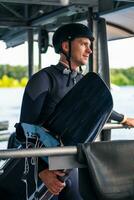 Confident smiling wakeboarder in full gear with board staning on start dock photo