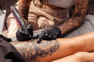 Professional tattoo master creating artistic masterpiece on female thigh photo