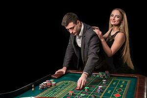 elegante Pareja a el casino apuesta en el ruleta, en un negro antecedentes foto