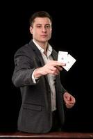 Young caucasian man wearing suit holding two aces in his hand on black background. Gambling concept. Casino photo