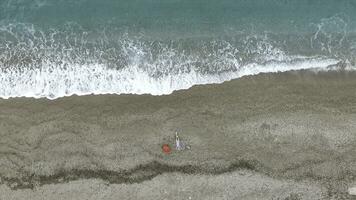 Young woman lying on the back near the waves of blue sea. Footage. Top view photo