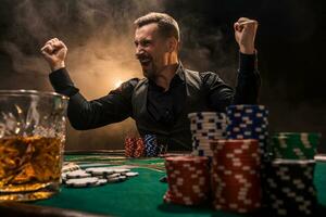 Young handsome man sitting behind poker table with cards and chips photo