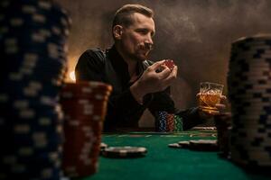 Young handsome man sitting behind poker table with cards and chips photo