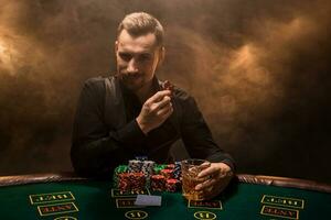 A young man in a business suit sitting at the poker table. Man gambles. The player at the gaming table playing cards. photo