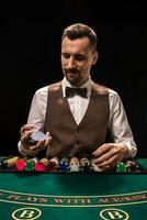 Portrait of a croupier is holding playing cards, gambling chips on table. Black background photo