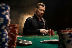 Young handsome man sitting behind poker table with cards and chips photo
