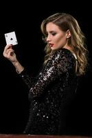 Young woman holding playing cards against a black background photo