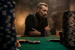 Young handsome man sitting behind poker table with cards and chips photo