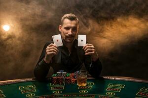 Bearded man showing poker cards on smoke black background photo