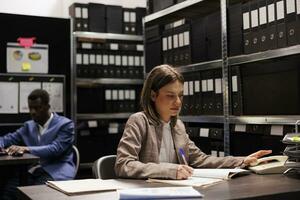 Police officer reading confidential report, working late at night at criminal case in arhive room. Private detective analyzing crime scene surveillance footage, searching for new clues photo