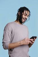 Happy arab man chatting online in social media network and laughing. Smiling young person with cheerful emotions scrolling internet pages and sending message on mobile phone photo