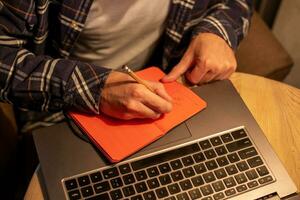 Cropped image of casual business man or freelancer planning his work on notebook, working on laptop computer with smart phone, cup of coffee on table at coffee shop or home office. photo