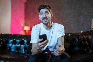 Young fan man watching football game on television celebrating g photo