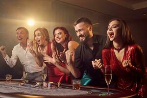 Group of a young rich friends are playing poker in casino. photo