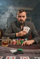 Handsome bearded man is playing poker sitting at the table in casino. photo