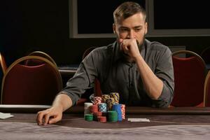 hermoso barbado hombre es jugando póker sentado a el mesa en casino. foto