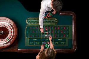 hombre crupier y mujer jugando ruleta a el mesa en el casino. parte superior ver a un ruleta verde mesa con un cinta medida. foto