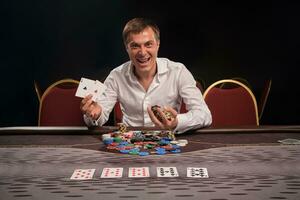 hermoso emocional hombre es jugando póker sentado a el mesa en casino. foto