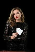 Young woman holding playing cards against a black background photo