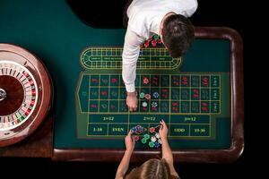 hombre crupier y mujer jugando ruleta a el mesa en el casino. parte superior ver a un ruleta verde mesa con un cinta medida. foto