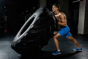 training - man flipping tire in gym photo