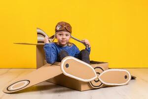 Little dreamer girl playing with a cardboard airplane. Childhood. Fantasy, imagination. photo