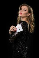 Young woman holding playing cards against a black background photo