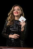 Young woman holding playing cards against a black background photo