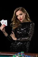 Young woman holding playing cards against a black background photo