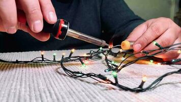 hombre preparando luces para decorando casa para Navidad vacaciones, de cerca. masculino manos cerca arriba reparando un eléctrico guirnalda. video