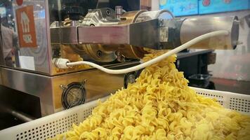 fabbricazione pasta nel il macchina. fabbricazione pasta. crudo fusilli è preparato nel un' privato ristorante. il giallo pasta cascate in il contenitore. video