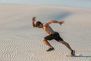 Fit man running fast on the sand. Powerful runner training outdoor on summer. photo