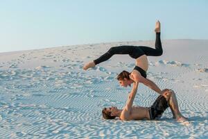 Pareja haciendo yoga ejercicios en arena al aire libre. aptitud física, deporte, personas y estilo de vida concepto foto