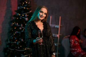 Beautiful young woman with glass of champagne at Christmas party photo